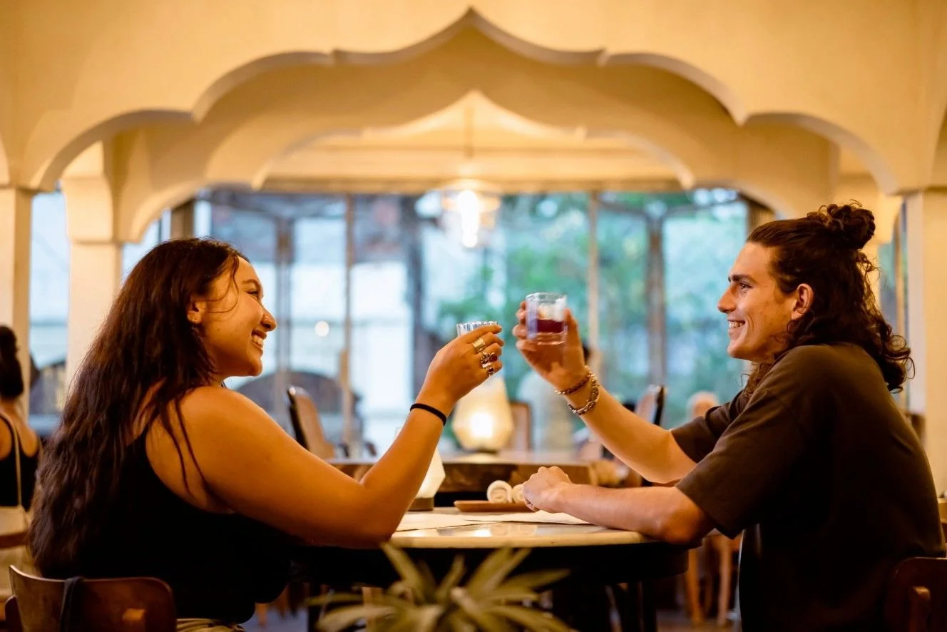 A couple toasting with cocktails while enjoying a relaxed evening at Pesona Lounge in Ubud.