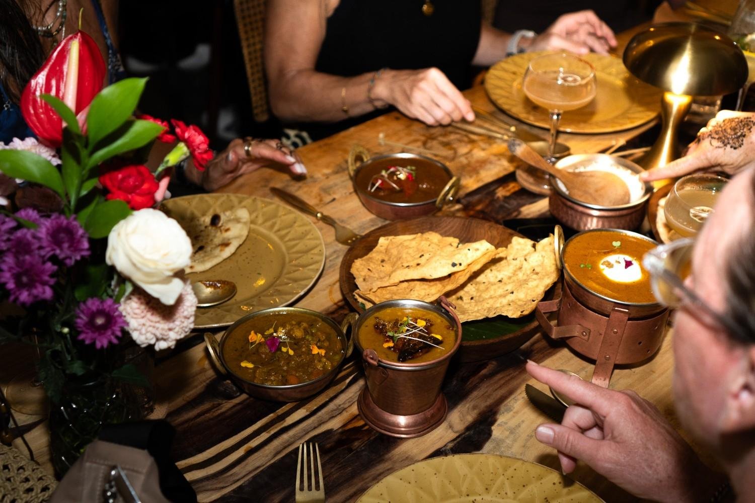 Guests sharing a traditional Indian dinner with naan, curries, and side dishes at a restaurant in Ubud.