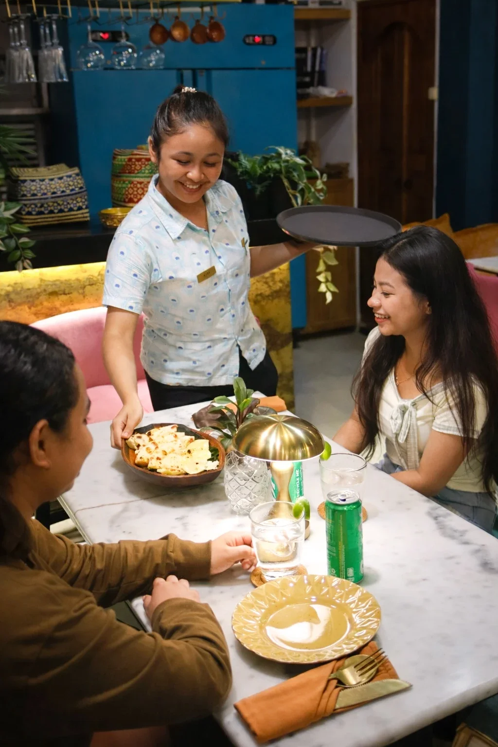Friendly staff serving freshly baked naan to guests at Pesona Lounge, an Indian restaurant in Ubud.