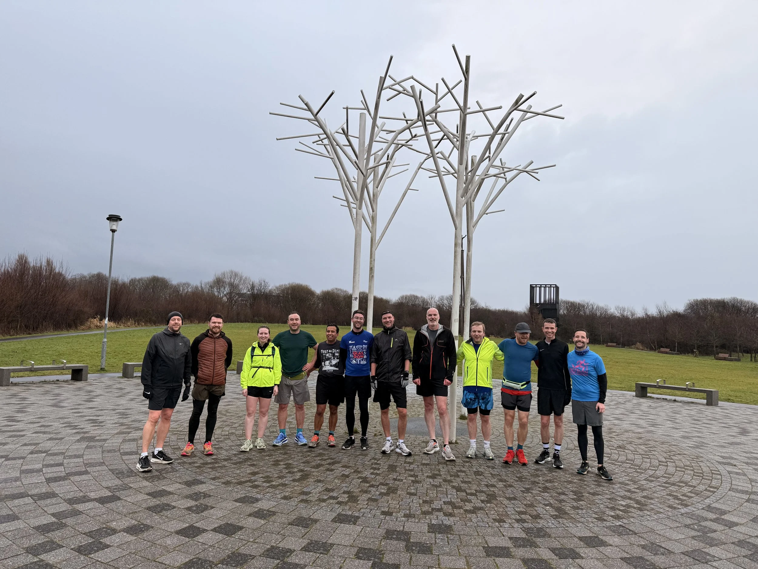 An image of Glasgow FrontRunners members in front of a metal sculpture in a park.