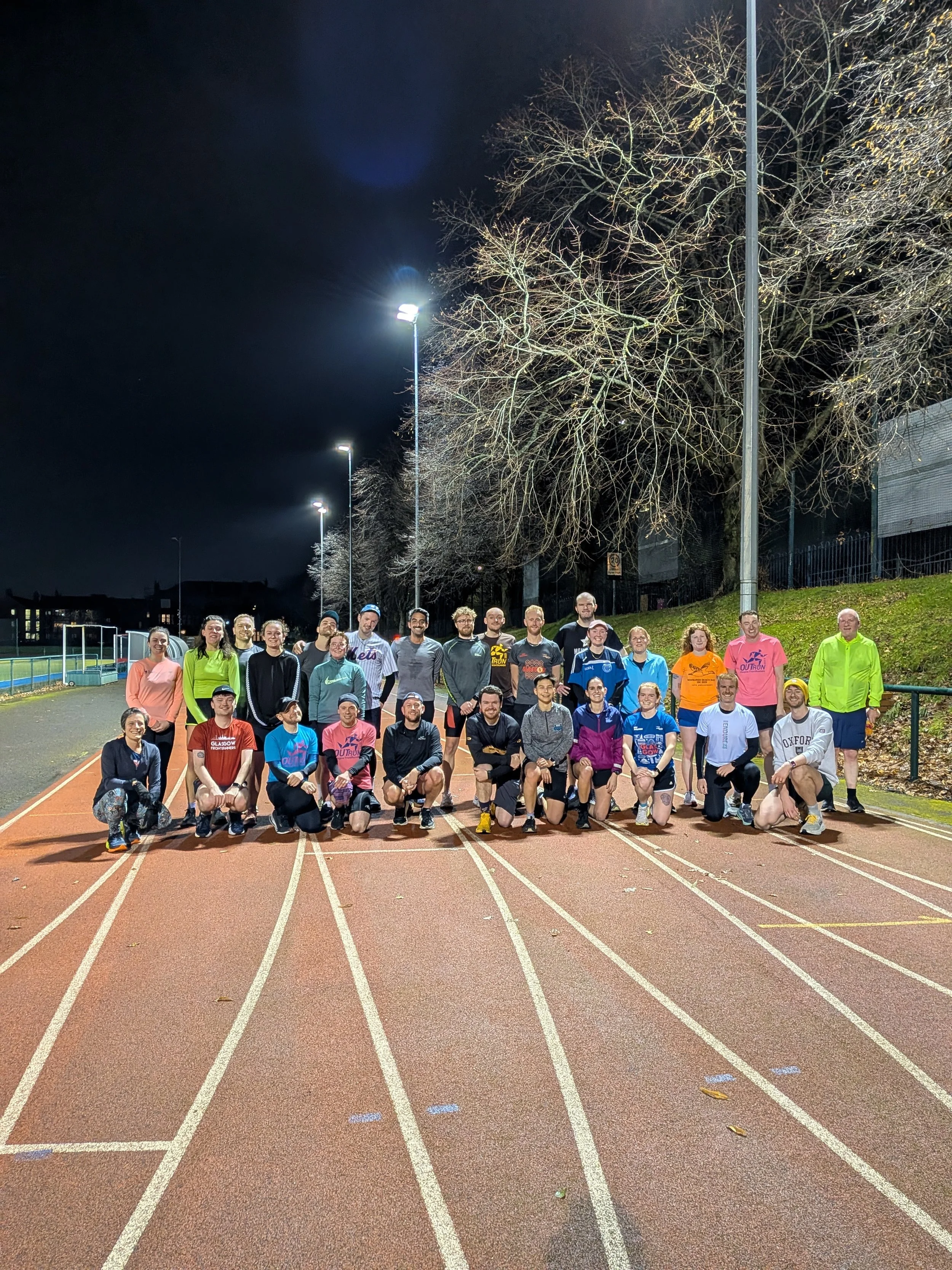 An Image of Glasgow FrontRunner members at a track session in various colourful running gear
