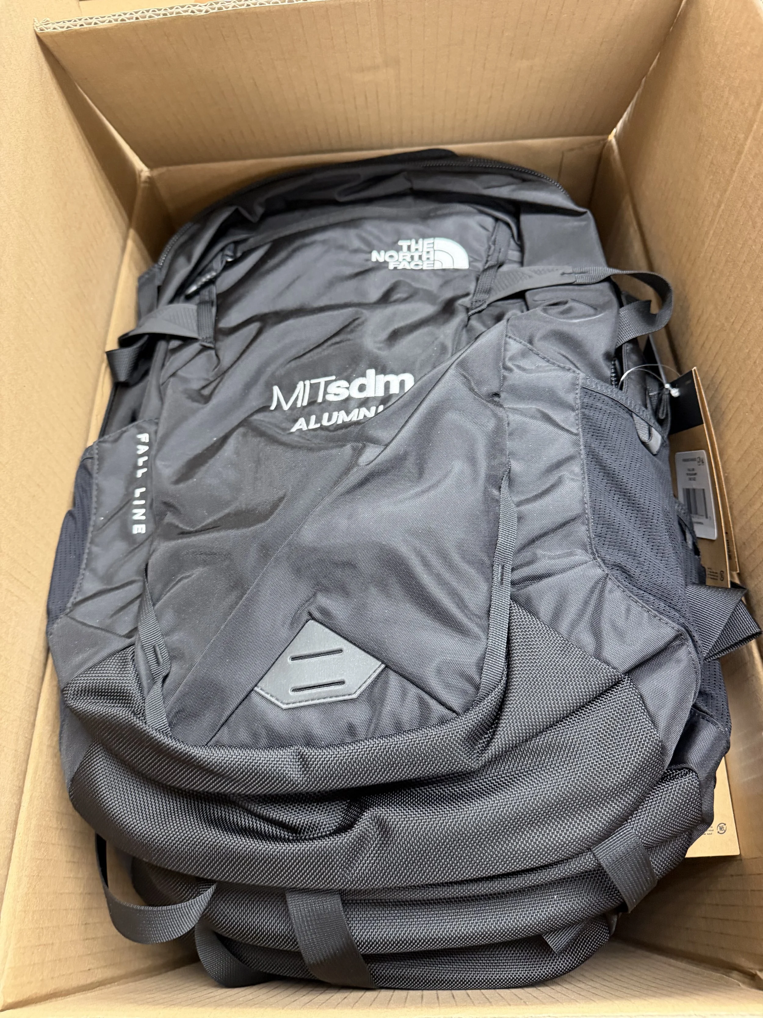 A black North Face backpack inside a cardboard box.