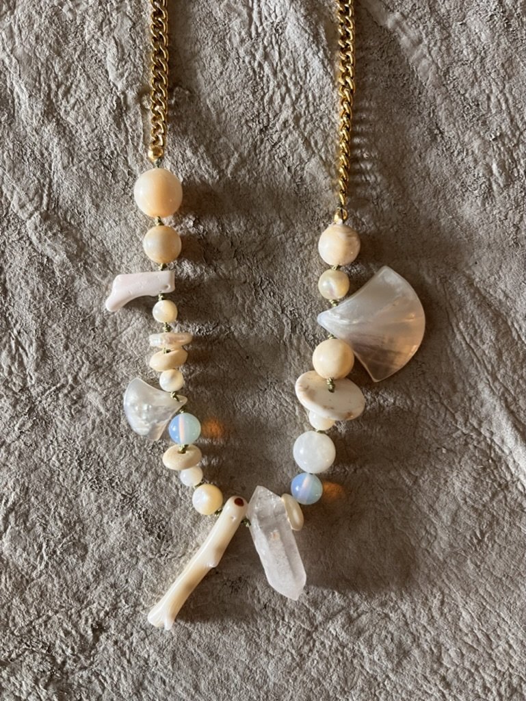 On-trend bohemian necklace that combines subtle tones of white coral, mother of pearl, bone, and crystal with a classic gold plated chain for a fun, stylish and unique look.