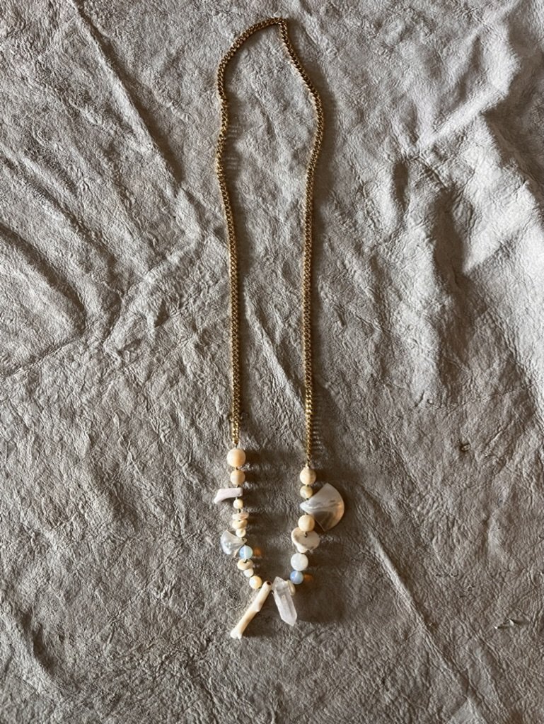 On-trend bohemian necklace that combines subtle tones of white coral, mother of pearl, bone, and crystal with a classic gold plated chain for a fun, stylish and unique look.