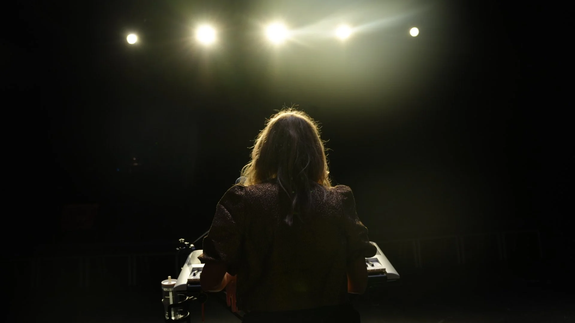 Michelle Lema in Bean vs. The Robots at keyboard, facing stage lights