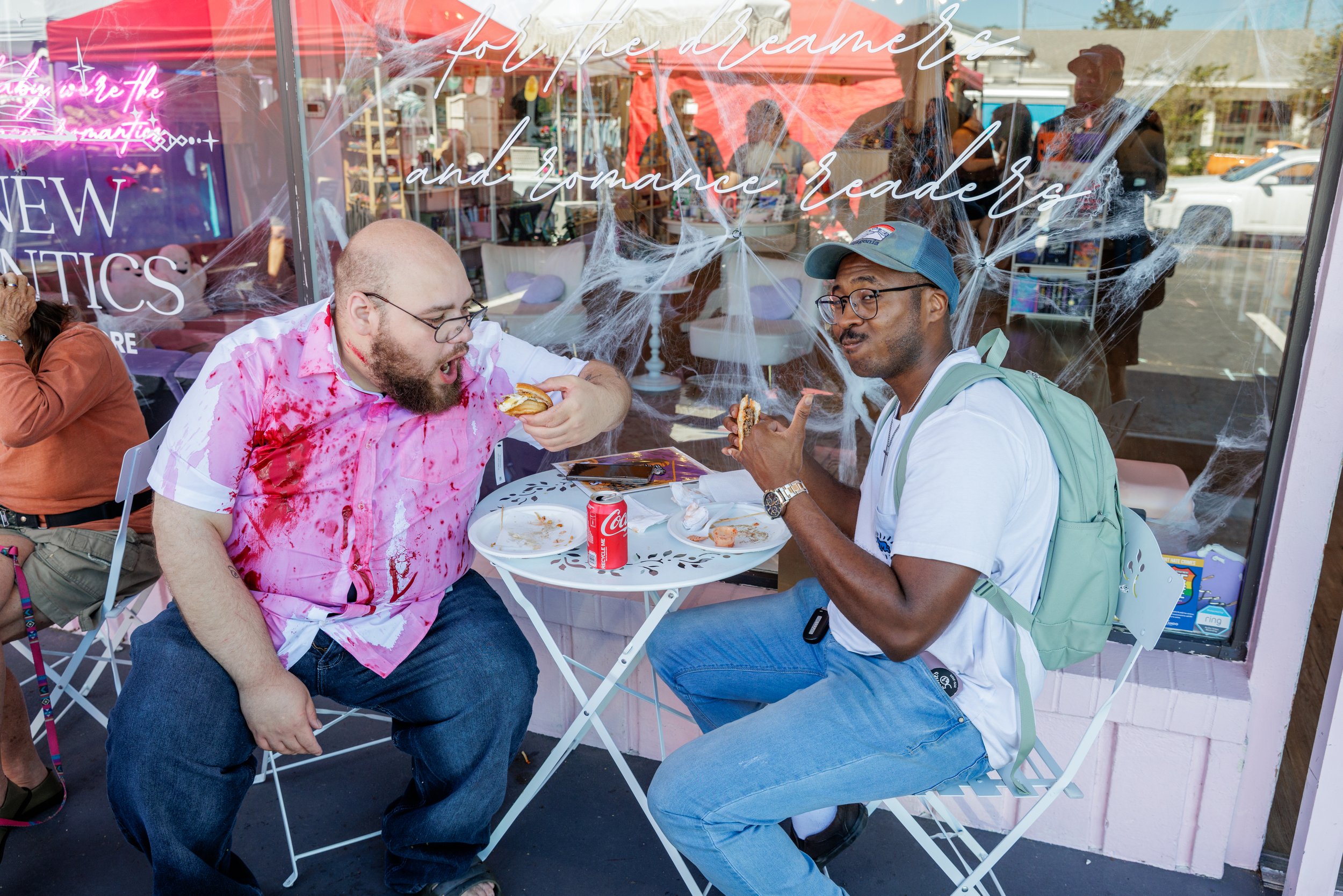 two men eating festival food at an outdoor table