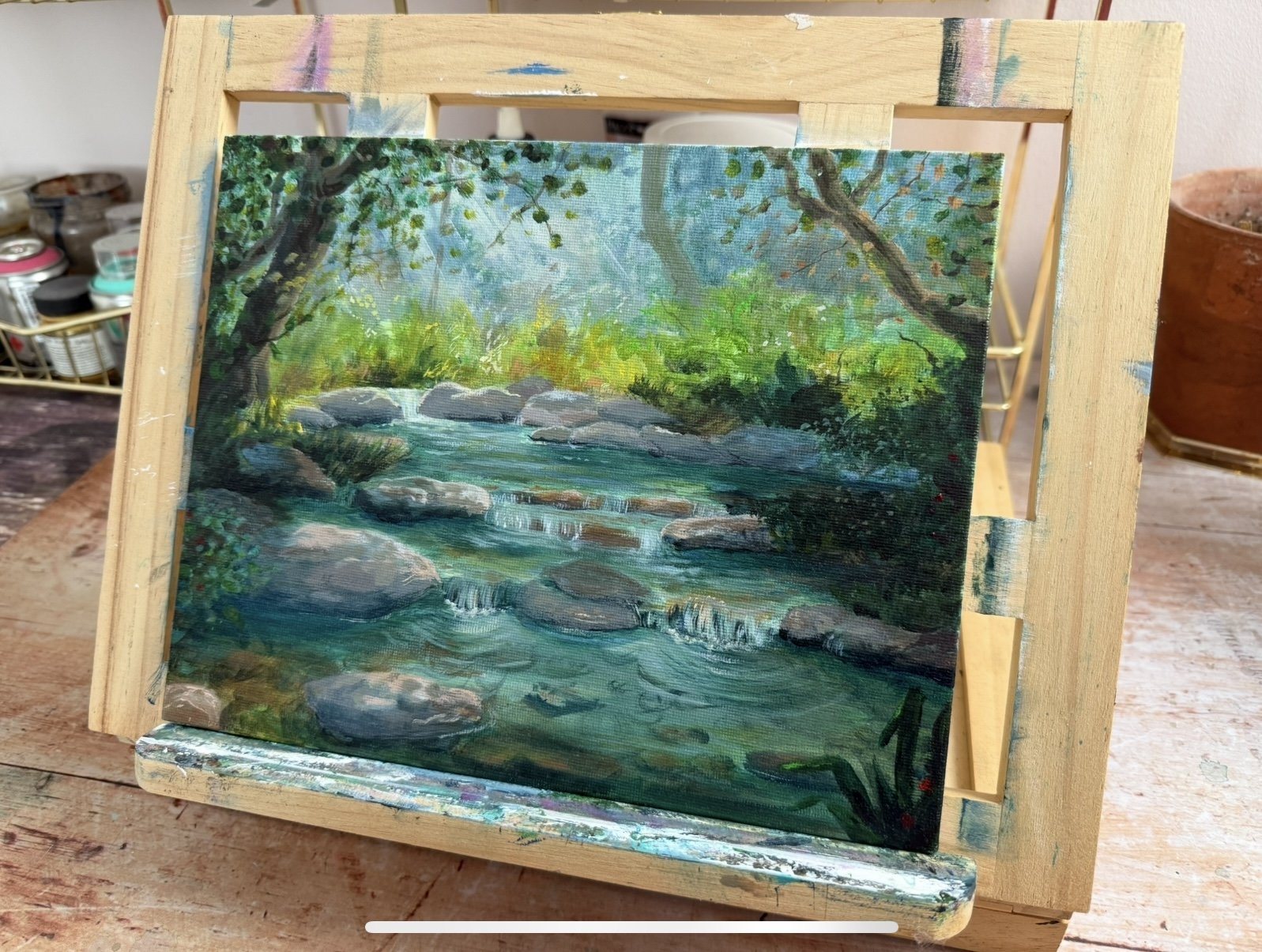 small canvas forest stream painting on easel