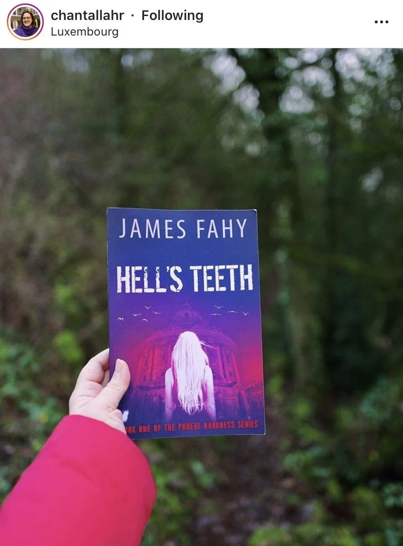 Person holding a book titled 'Hell's Teeth' by James Fahy in a wooded outdoor area.