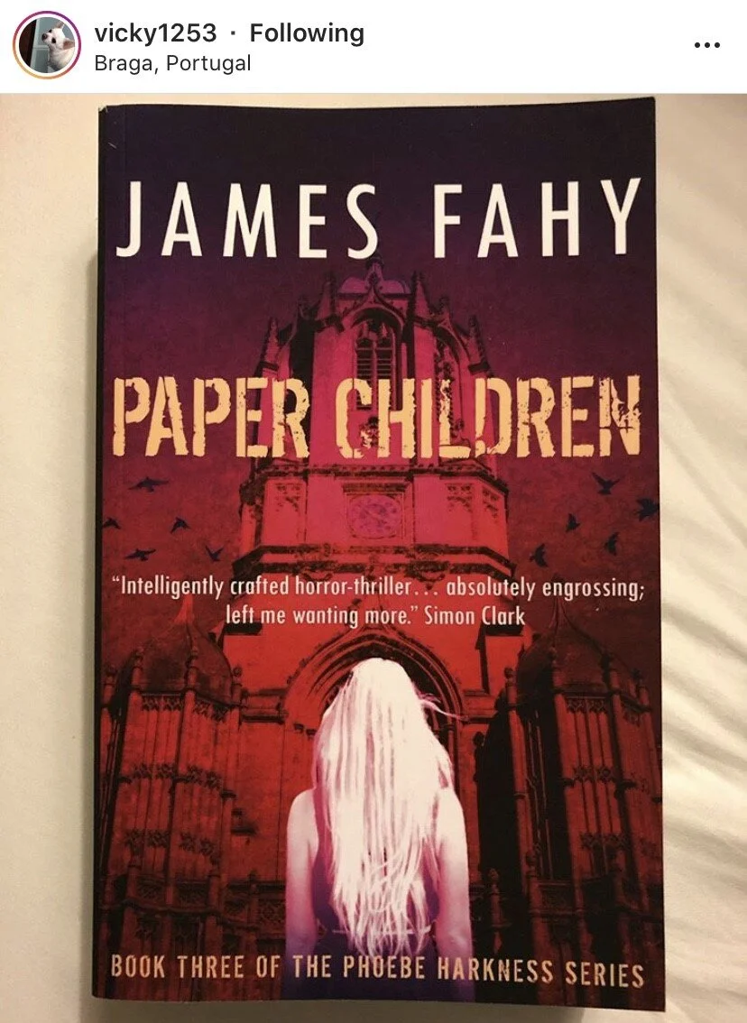 Book cover of 'Paper Children' by James Fahy. The cover shows a woman with long blonde hair facing away in front of a large, gothic-style building under a dark sky with birds.