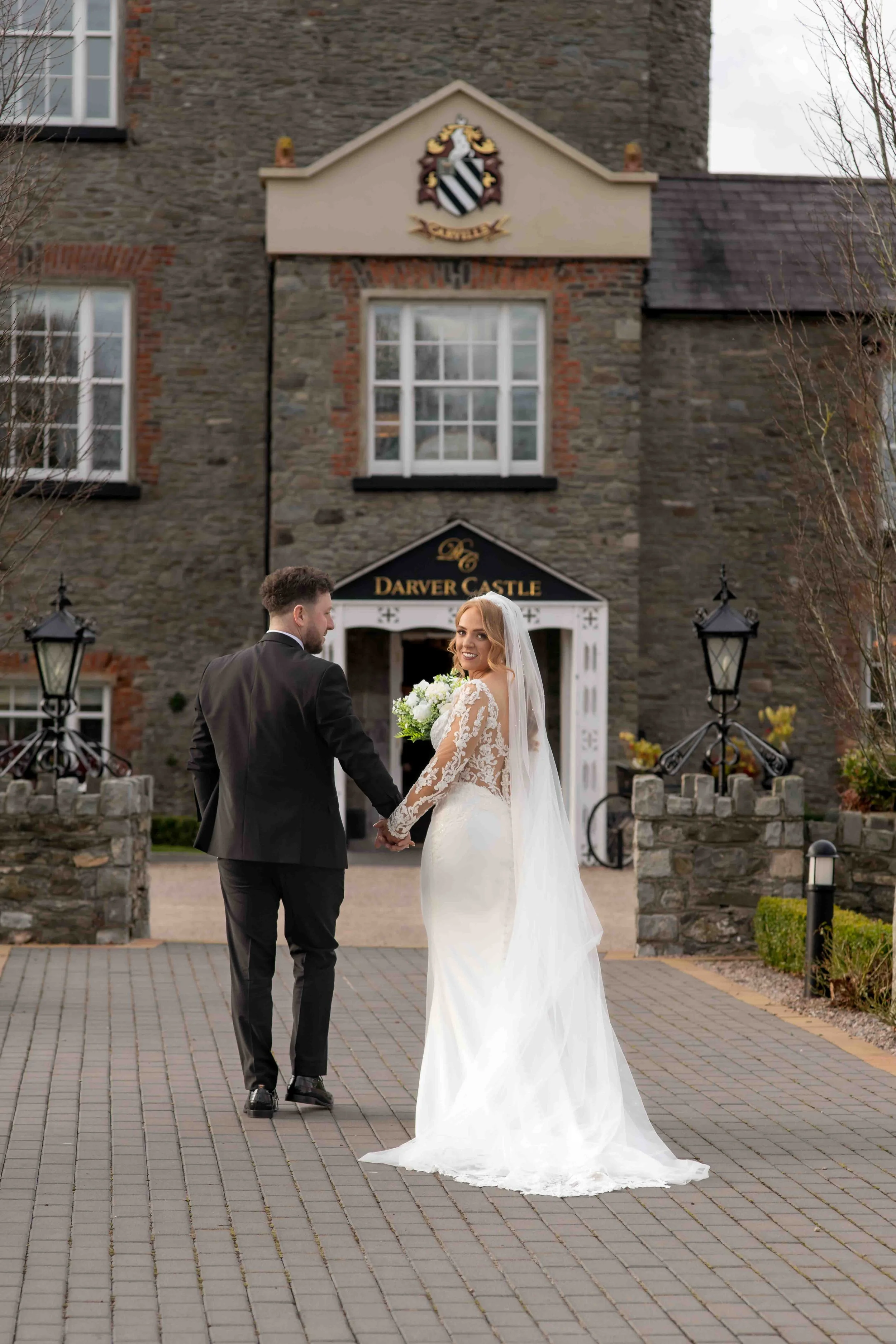 Bride and groom holding hands, walking towards Darver Castle.