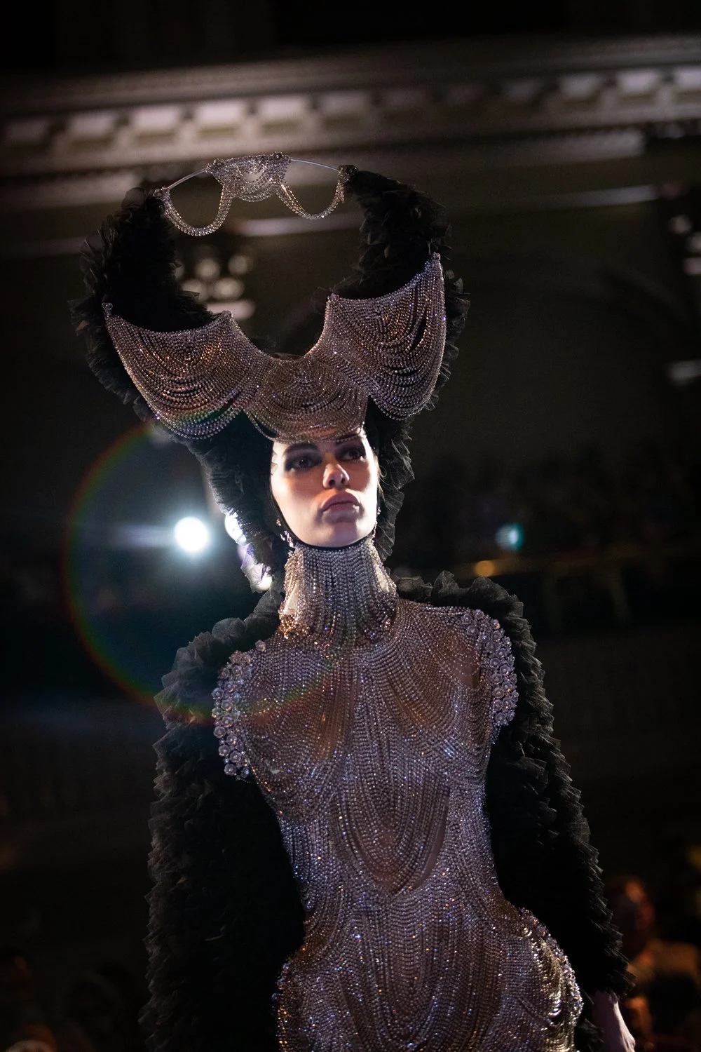 A model dressed in a large bejeweled outfit and headpeice.