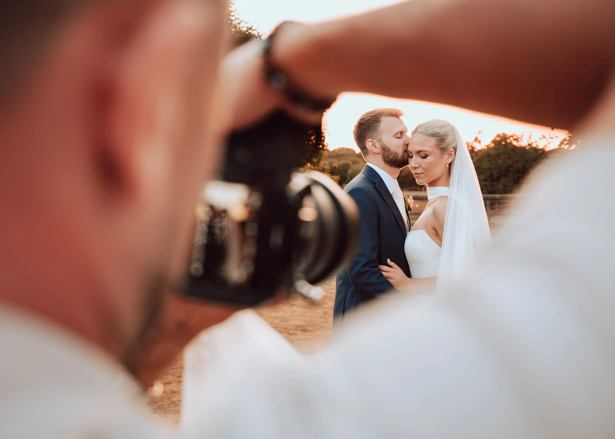 Behind the scenes wedding photo of Essex wedding photographer liam gillan taking a photo of beautiful couple at Sunset