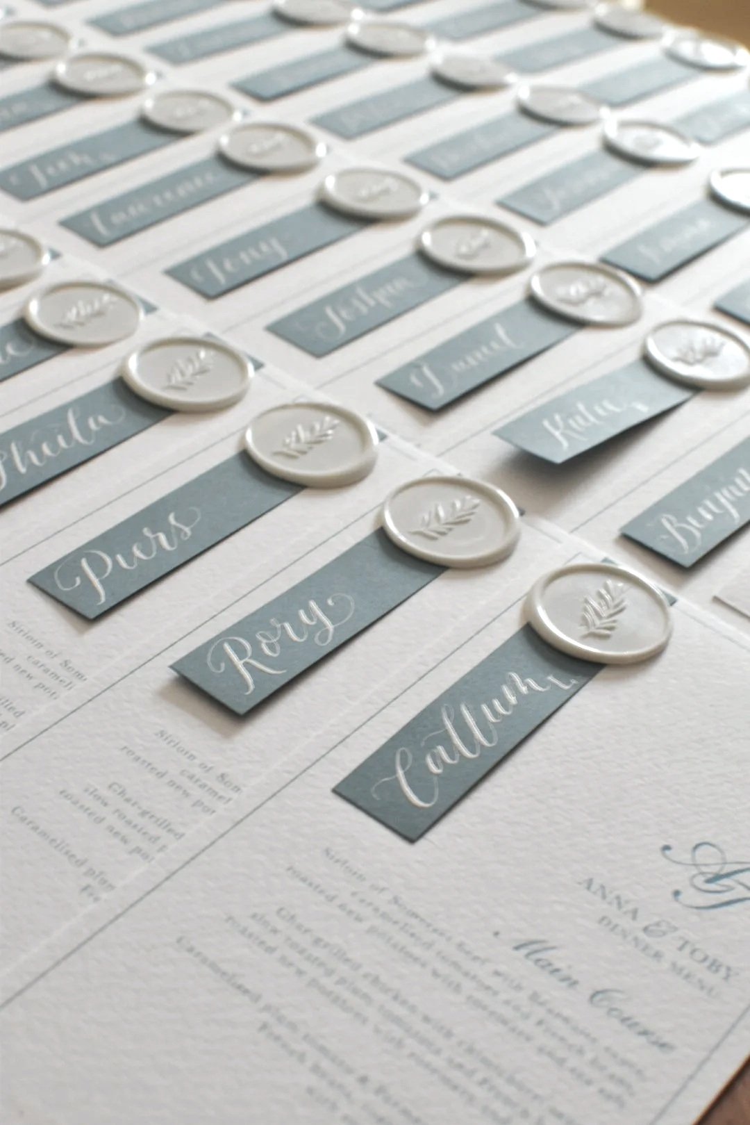 handwritten wedding place names on blue background with white wax seal