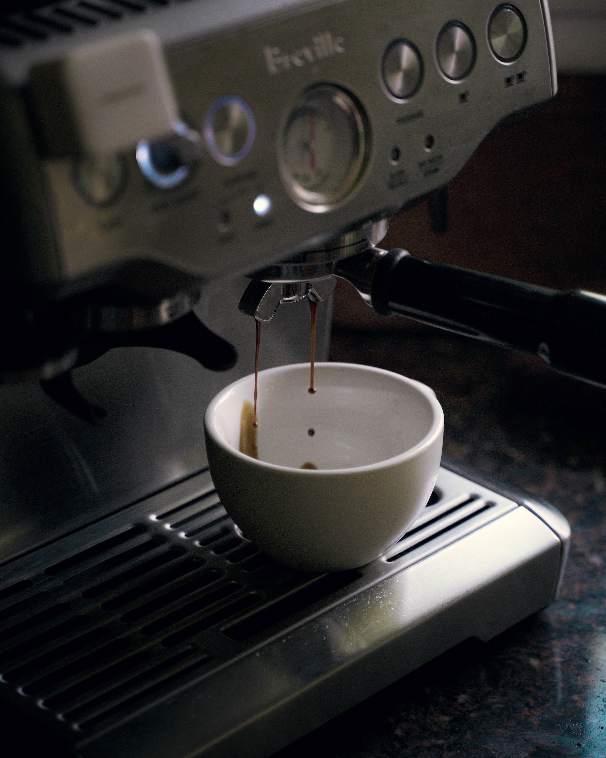 espresso dripping from Breville Barista Express portafilter into demitasse cup