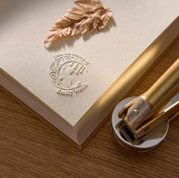 An embossed book page with the embosser next to it