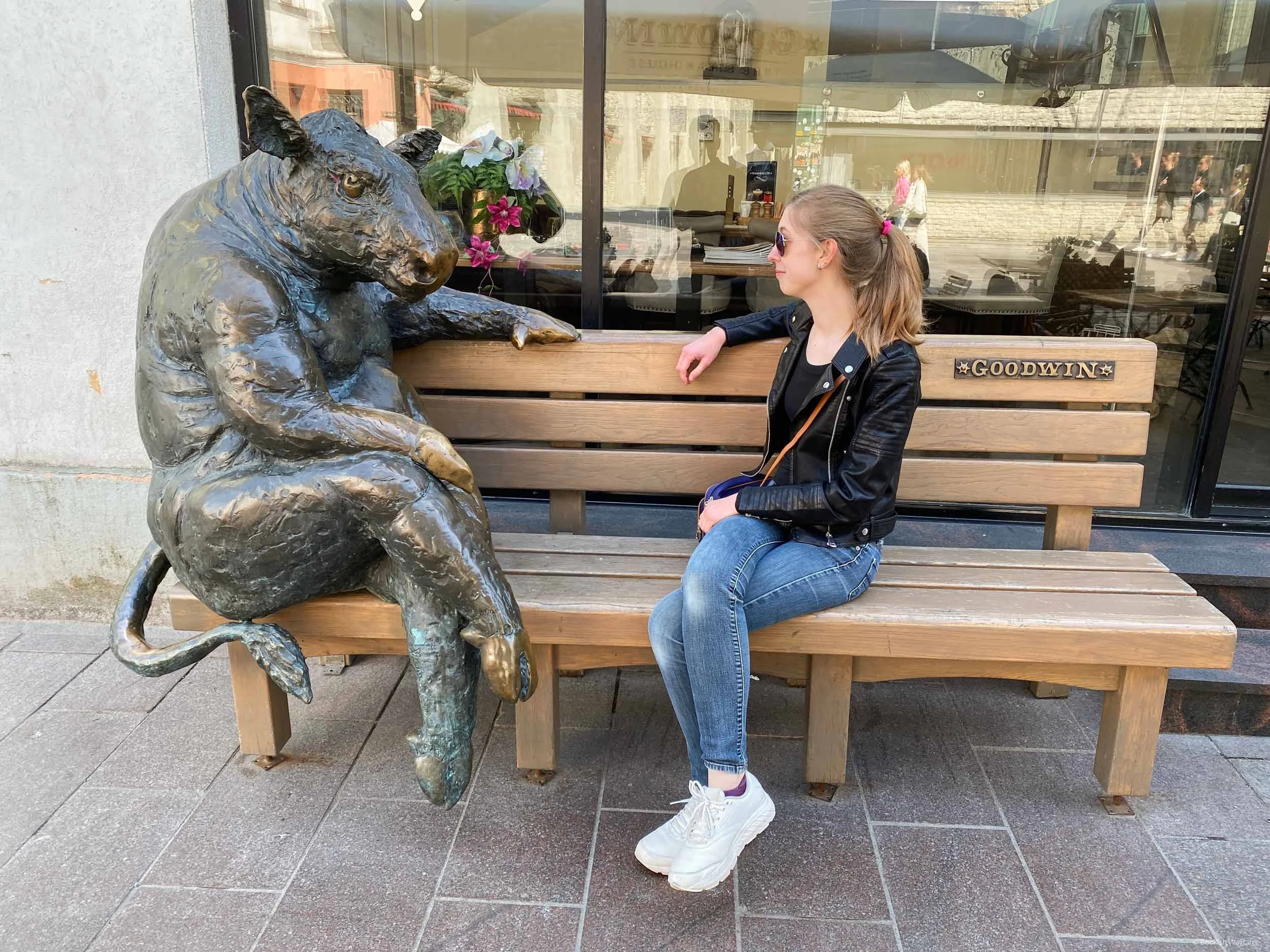 The author, Julia, sits on a wooden bench next to the Black Angus statue in Tallinn