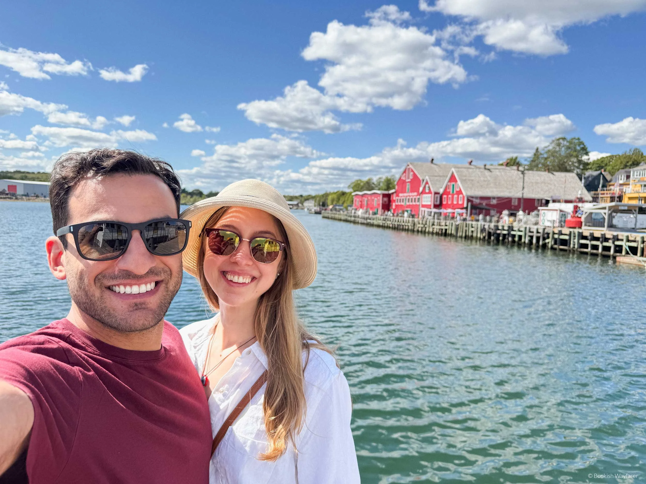 A couple smiles for a photo along the docks of Lunenburg, Nova Scotia