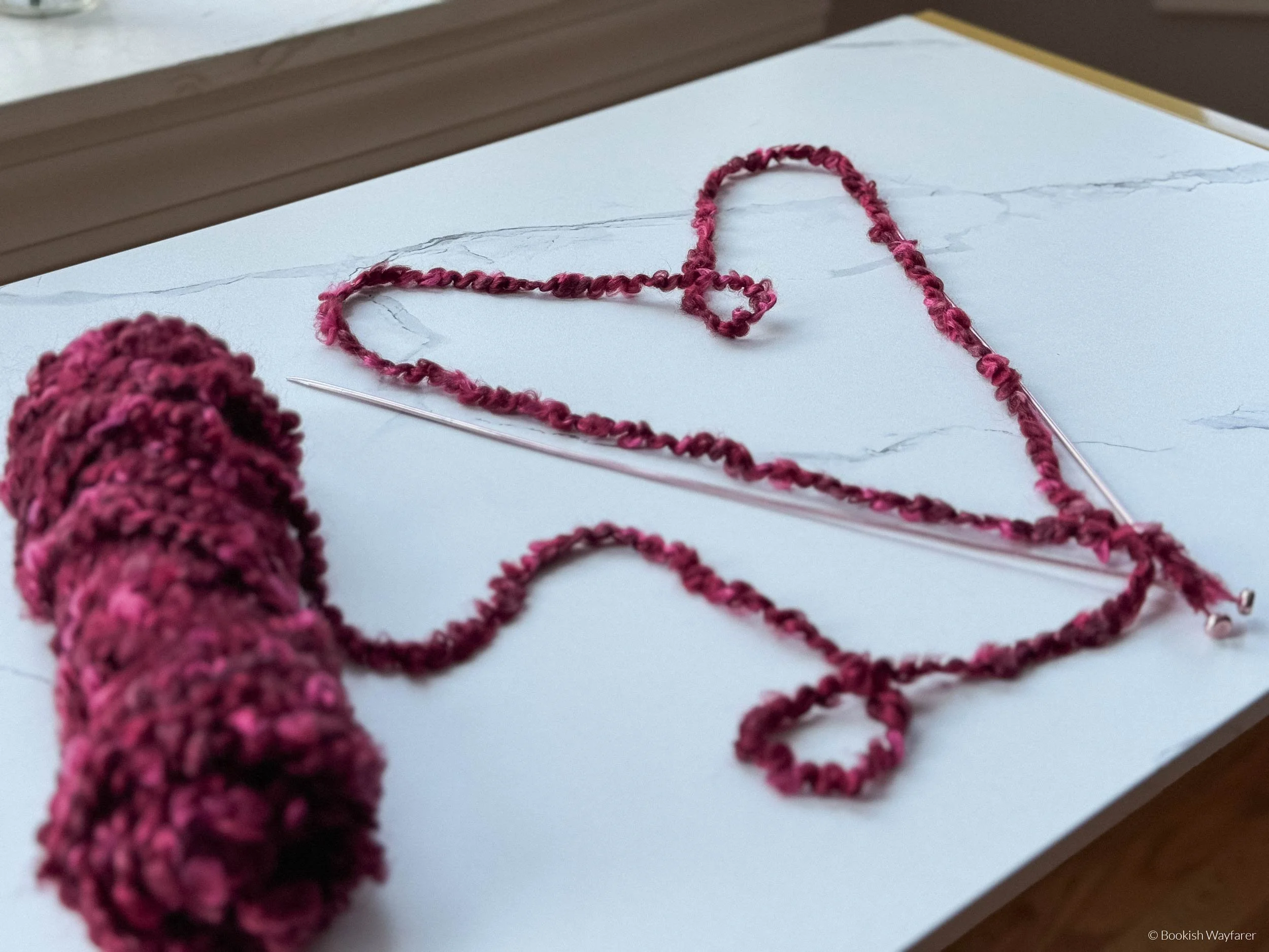 A heart made out of red yarn atop a white table