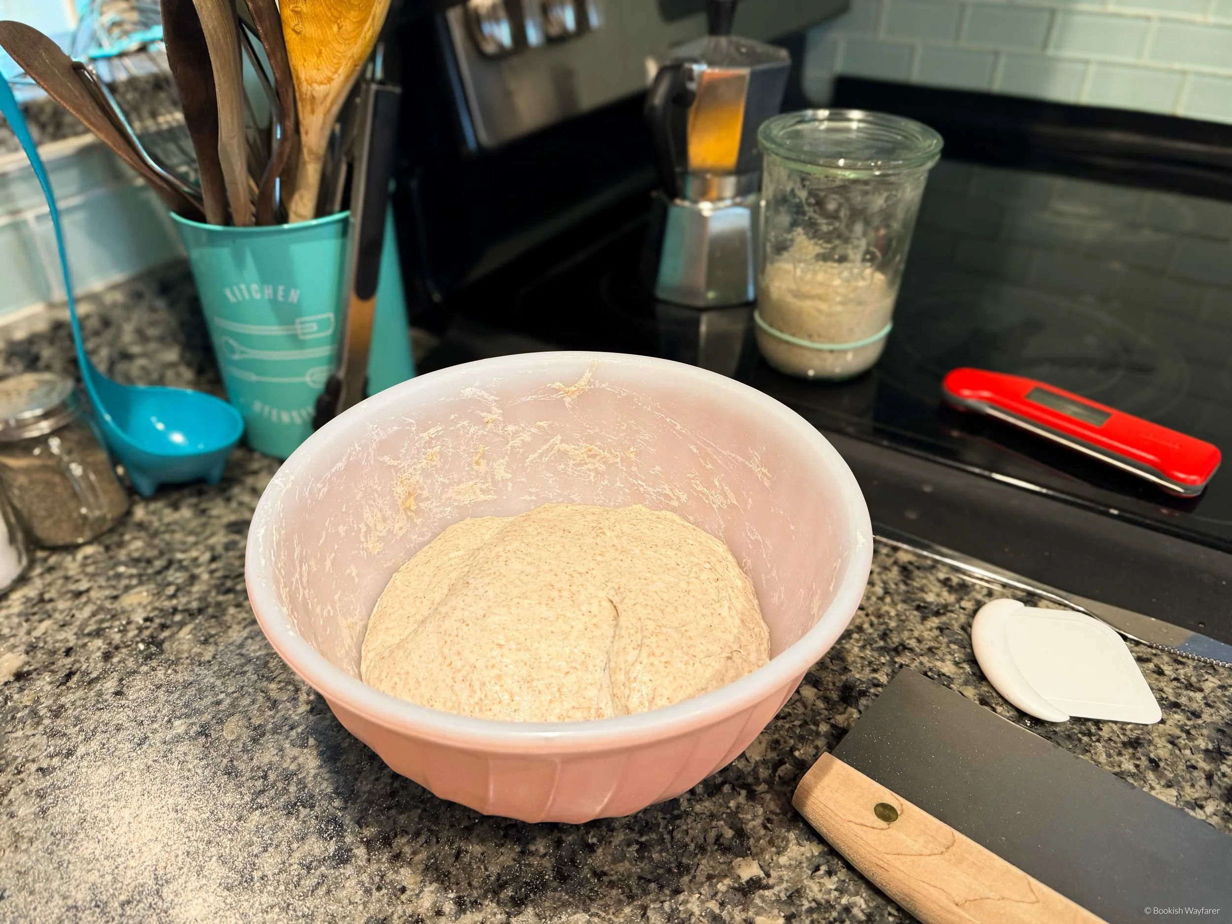 A bowl of proofing sourdough and various related bread-making tools
