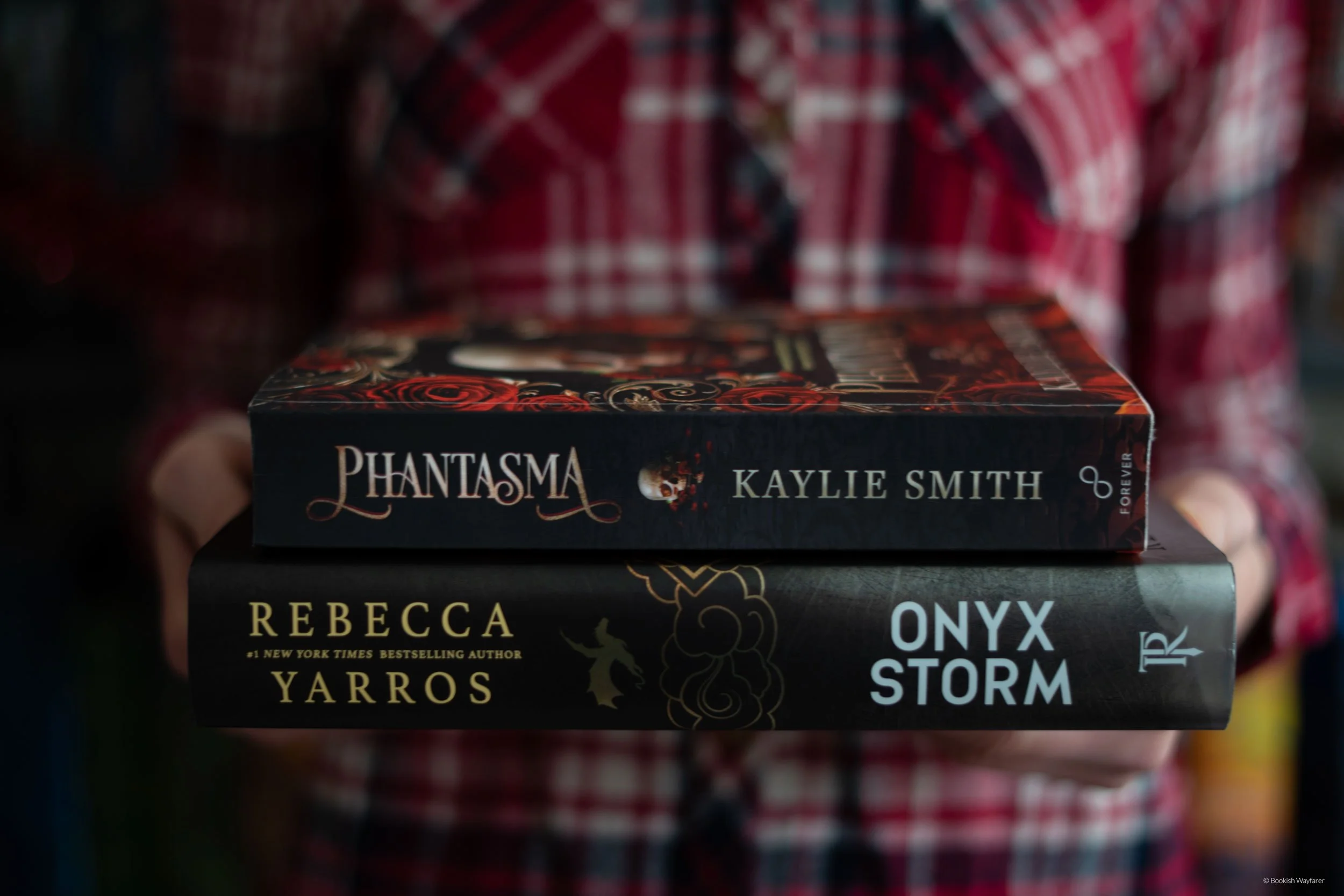 The author of this post holds the books Phantasma and Onyx Storm in front of her