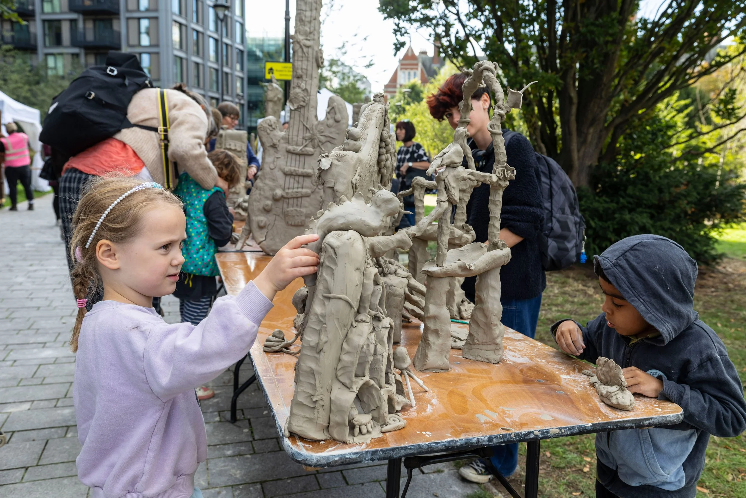 Children making large whimsical clay objects on a table in Queen's Park Gardens Croydon