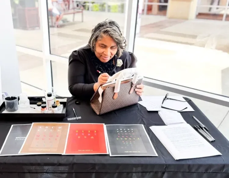 Angenise Rawls creating live calligraphy on a handbag