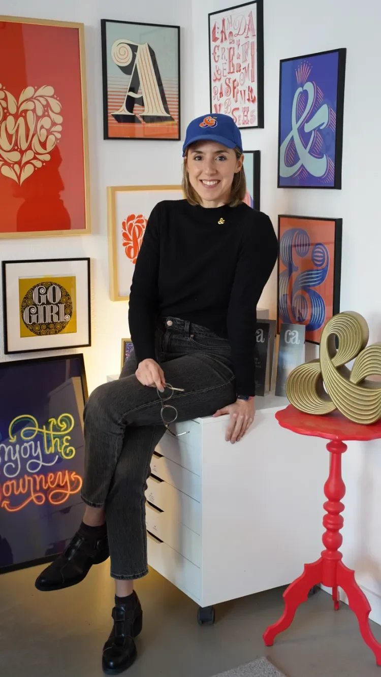 Martina Flor sitting in studio surrounded by her lettering designs