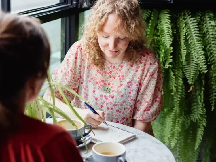 Laura Edralin journal writing in notebook in calm mindful cafe