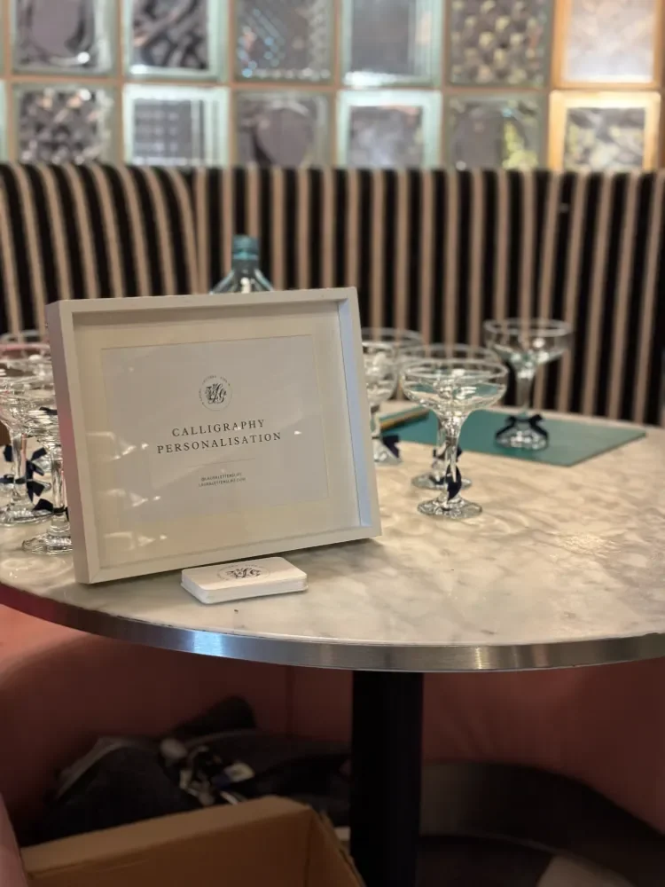 Calligraphy personalisation sign on a table with champagne glasses at a London event