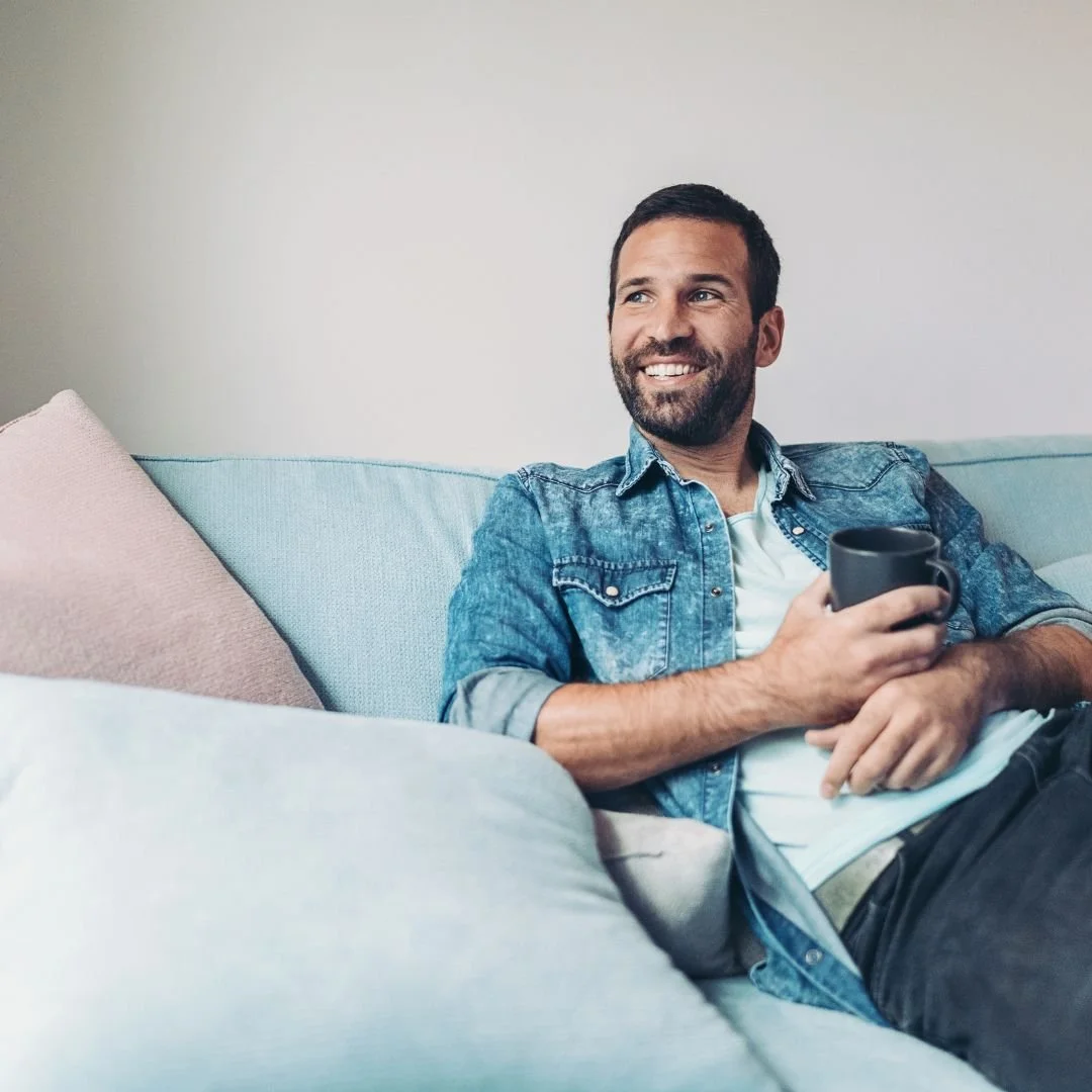 Man relaxing calmly at home with coffee, reflecting the sense of ease and balance supported by Mindfulness-Based Cognitive Therapy (MBCT) at Drishti Holistic Wellness