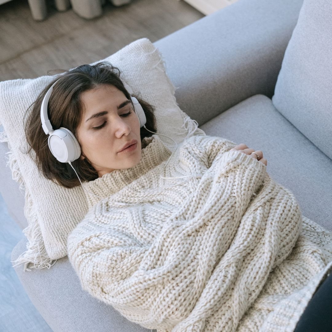 Woman relaxing with headphones in a calm, cozy setting, reflecting the safe, supportive environment of Ketamine-Assisted Psychotherapy (KAP) at Drishti Holistic Wellness