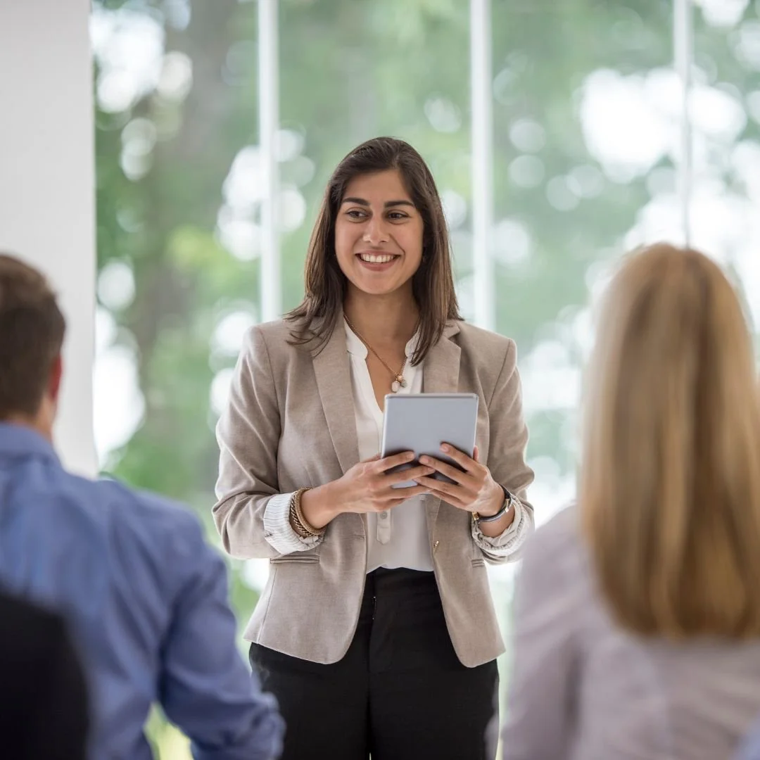 Woman leading a mindfulness and wellness training presentation to a small group, reflecting the workplace and community trainings offered at Drishti Holistic Wellness