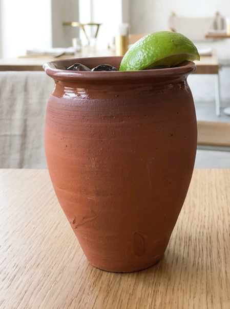 Handcrafted clay cantarito cup filled with an agua fresca and ice, served in a traditional Mexican style