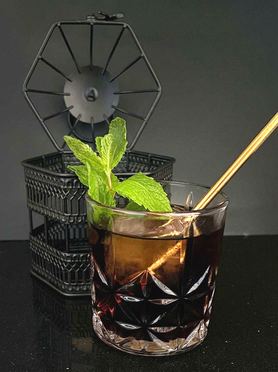 Black mini bird cage with cut glass cocktail glass inside with top of cage open