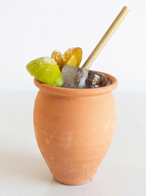 Traditional Mexican clay cantarito cocktail cup with a natural terracotta finish, shown on a plain background