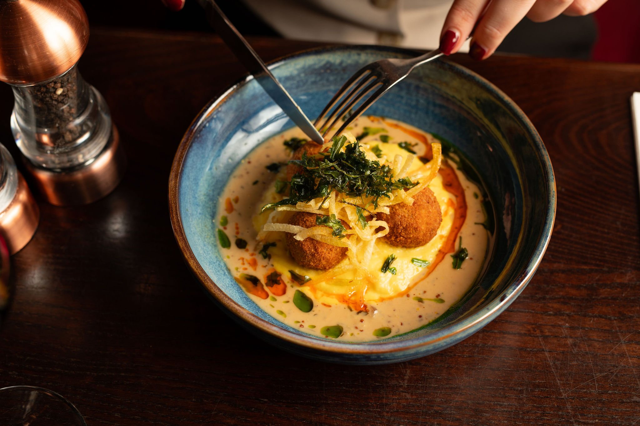 Experience a taste of Scotland with our Haggis, neeps, and tatties. Haggis bon bons, saffron neeps purée, fried tattie laces,
smoked whisky cream and crispy rocket.
