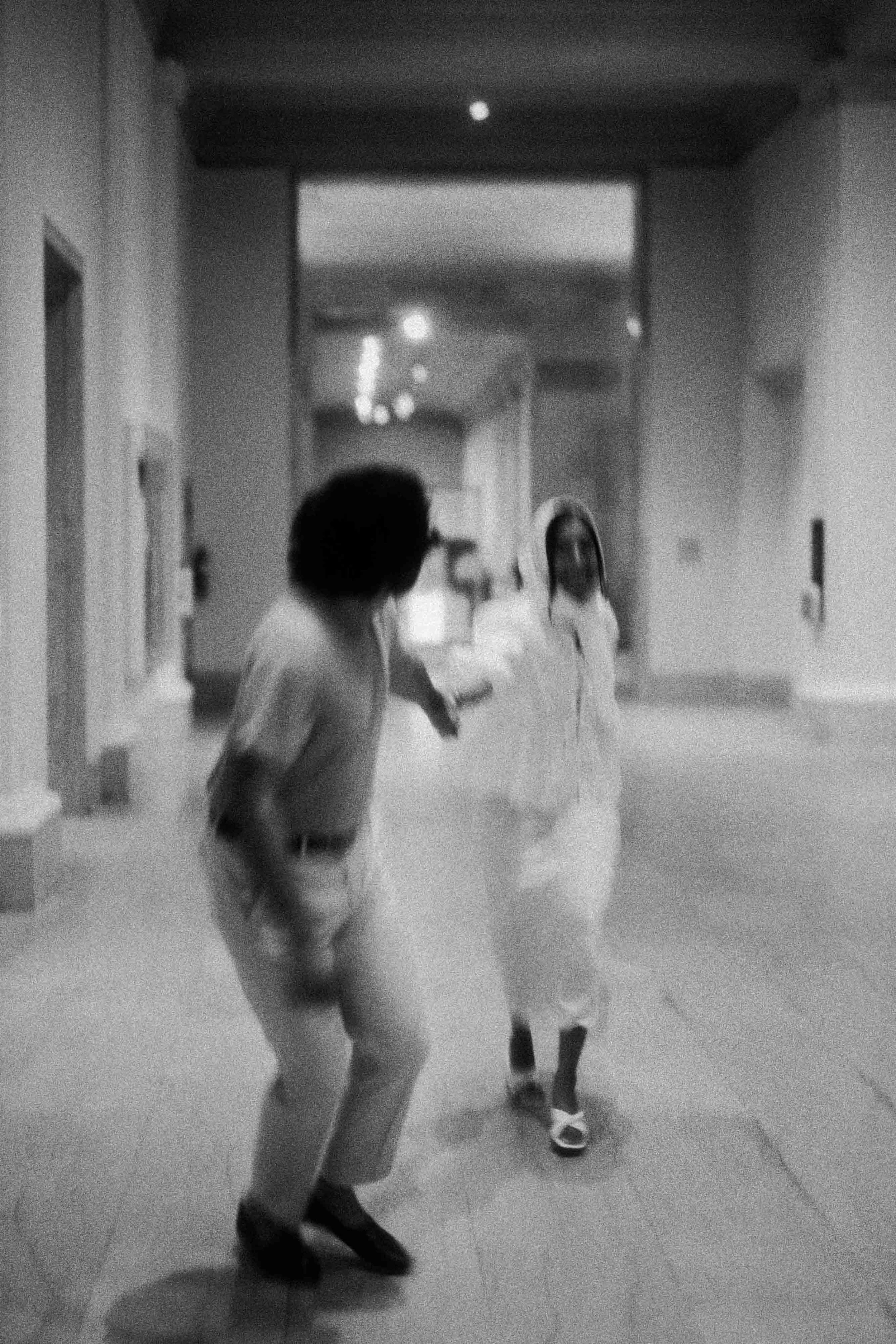 A black-and-white photo of two children dancing or playing together in a hallway.
