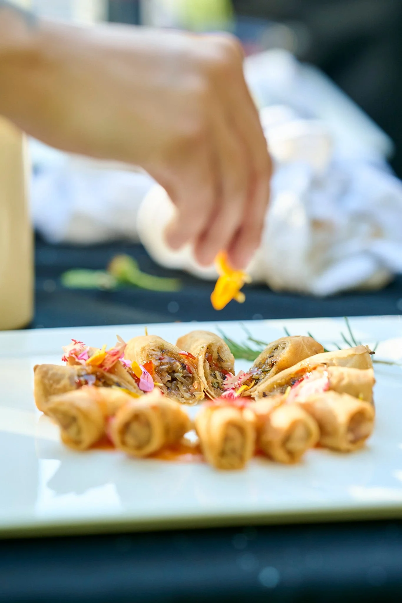 Crispy organic spring rolls prepared by Roux Catering by Dee Wagner Events and garnished with edible flowers.