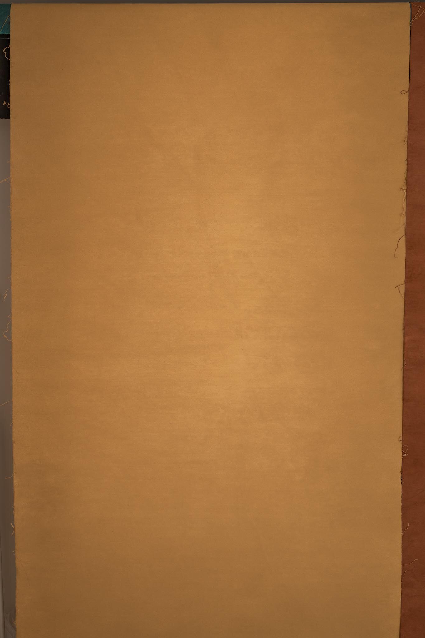 A blank, tan-colored piece of paper or cardboard lying on a flat surface.
