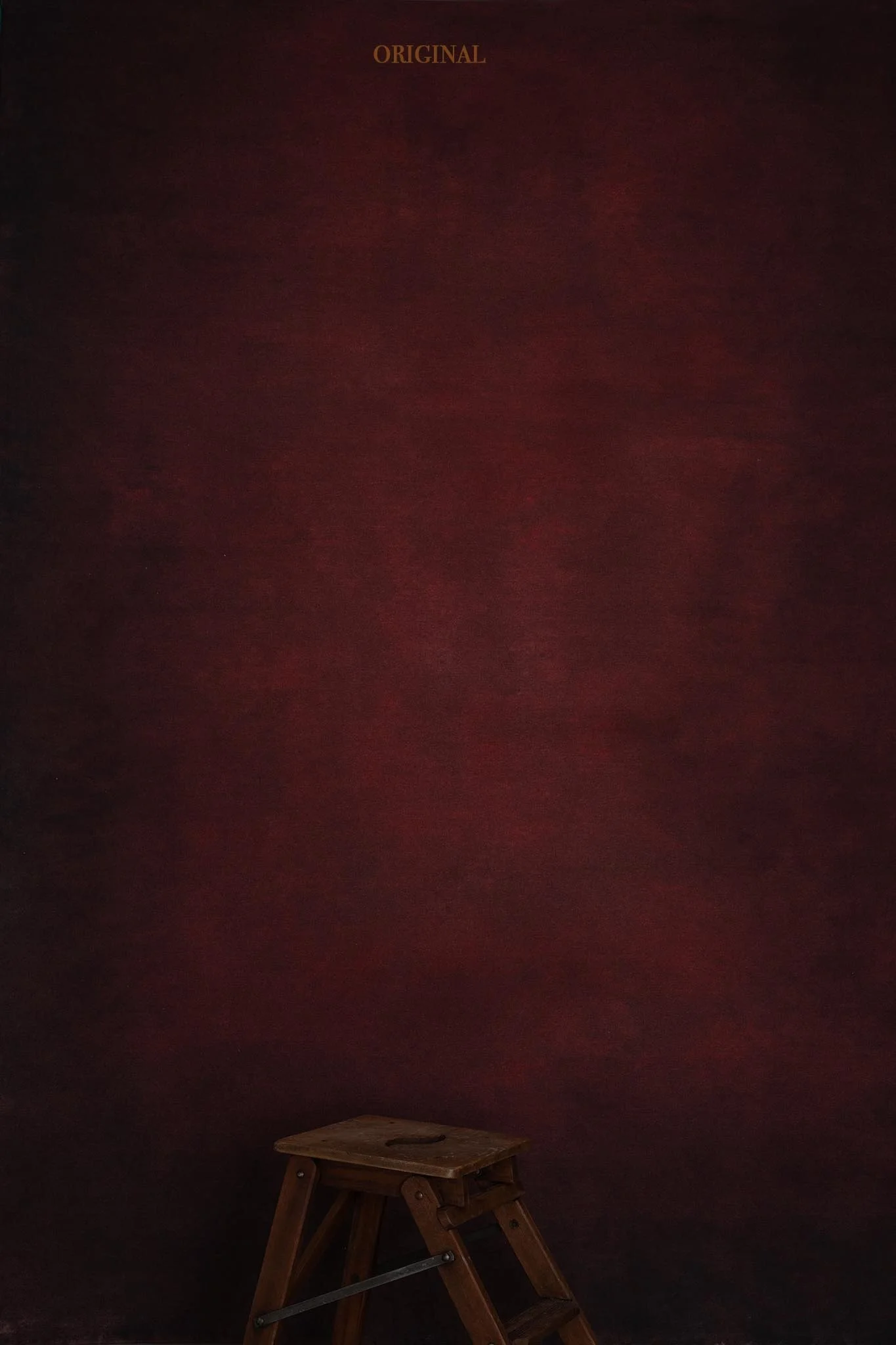 A small wooden step ladder on a dark surface against a deep red textured wall. "ORIGINAL" text is at the top of the image.