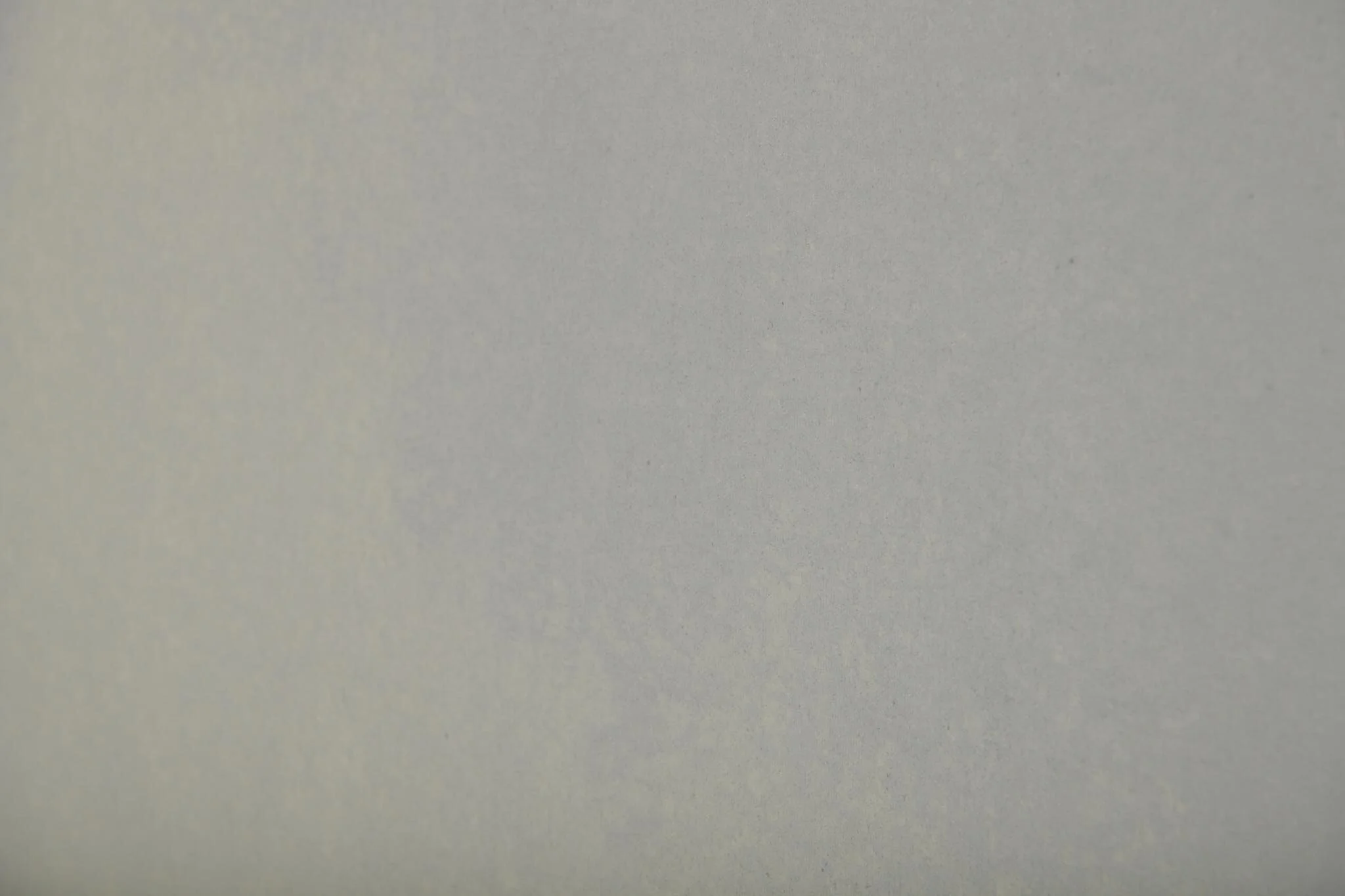 Close-up of a smooth, light gray surface, likely a wall or metal panel.