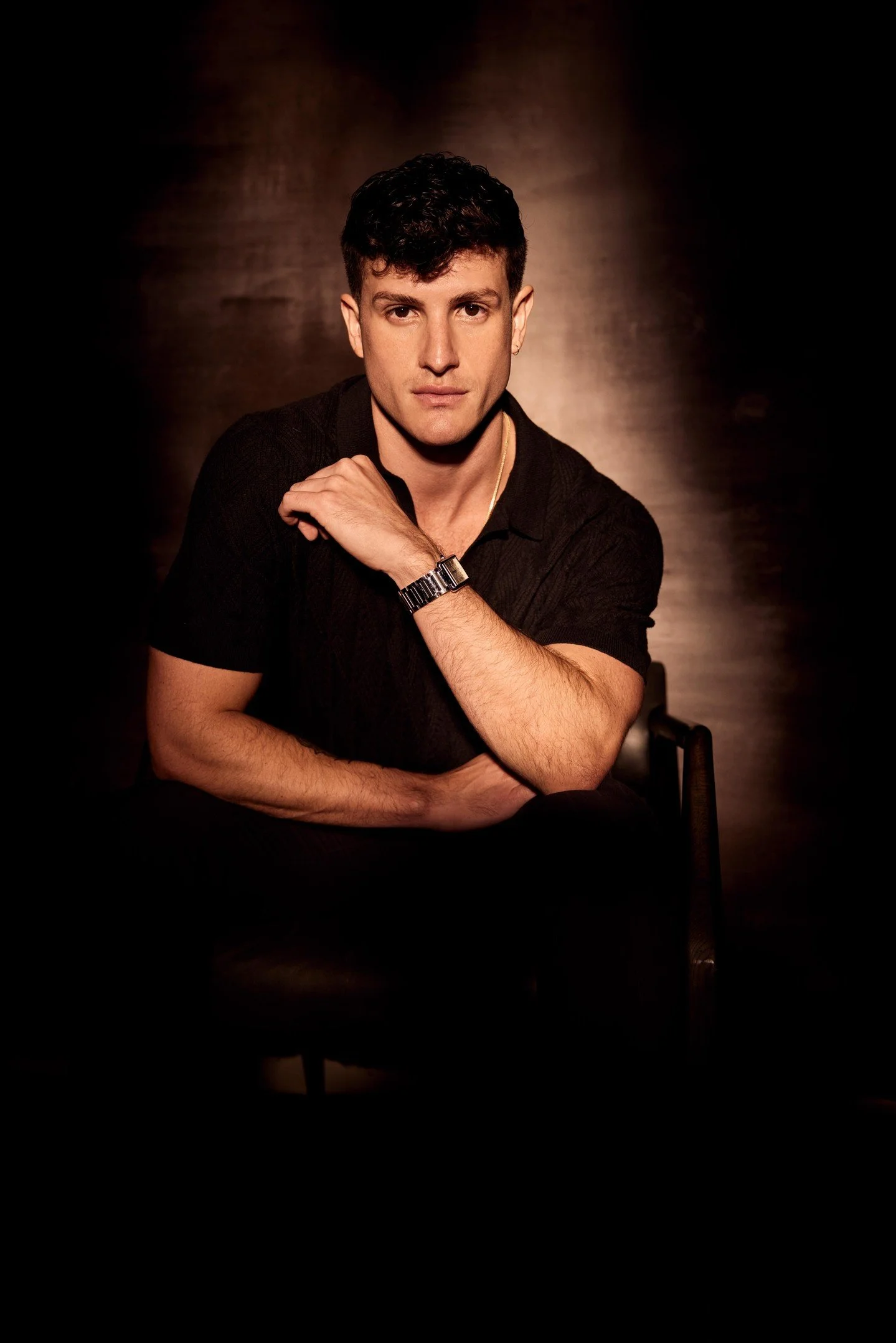 That warm soft illumination positioned from the front and slightly above is creating the most beautiful chiaroscuro drama across his face sculpting those subtle shadows that define his features and build genuine intimacy instead of that harsh spotlig