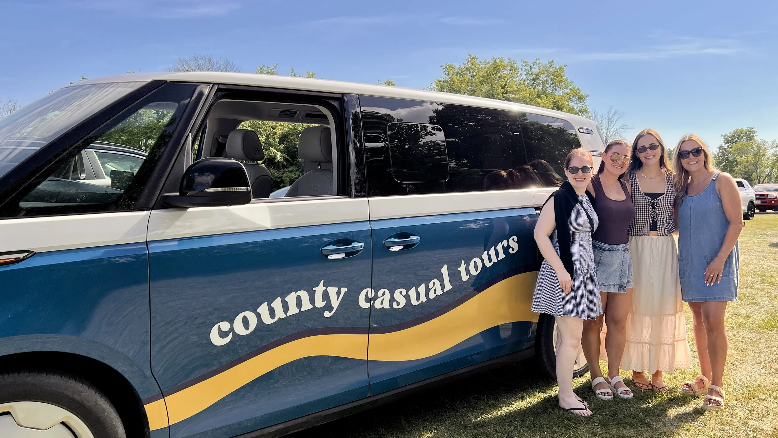 Four women standing next the County Casual Tour's VW ID Buzz vehicle