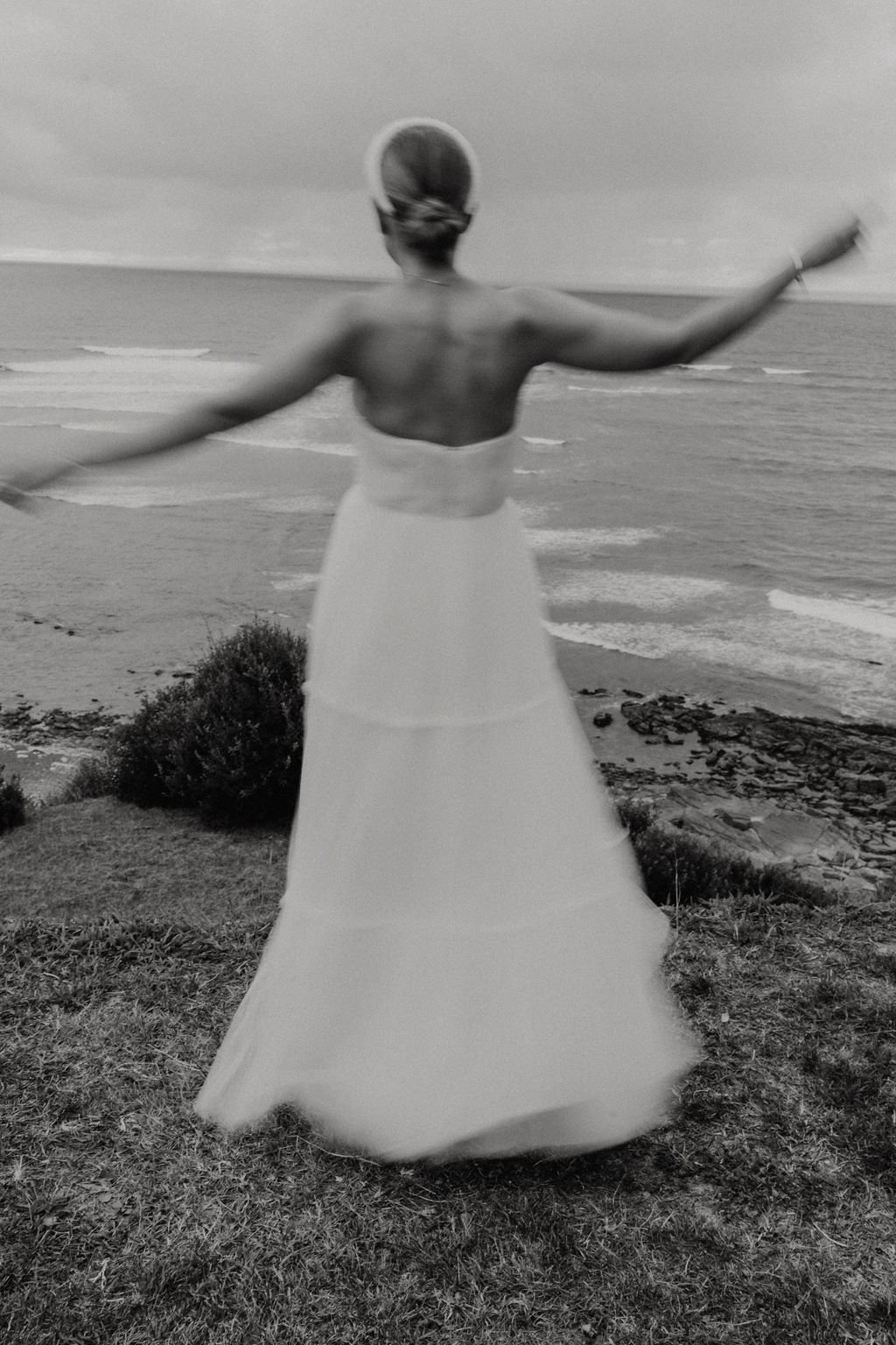 Personne en robe blanche devant la mer, vue de dos.