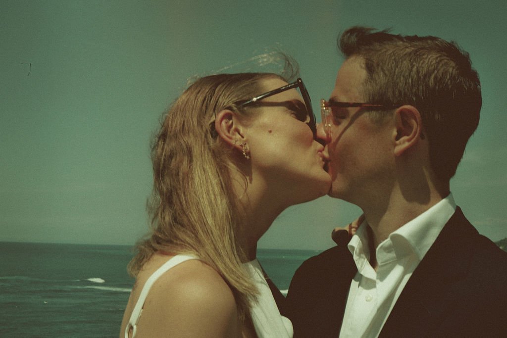 Un couple s'embrassant devant un paysage côtier.