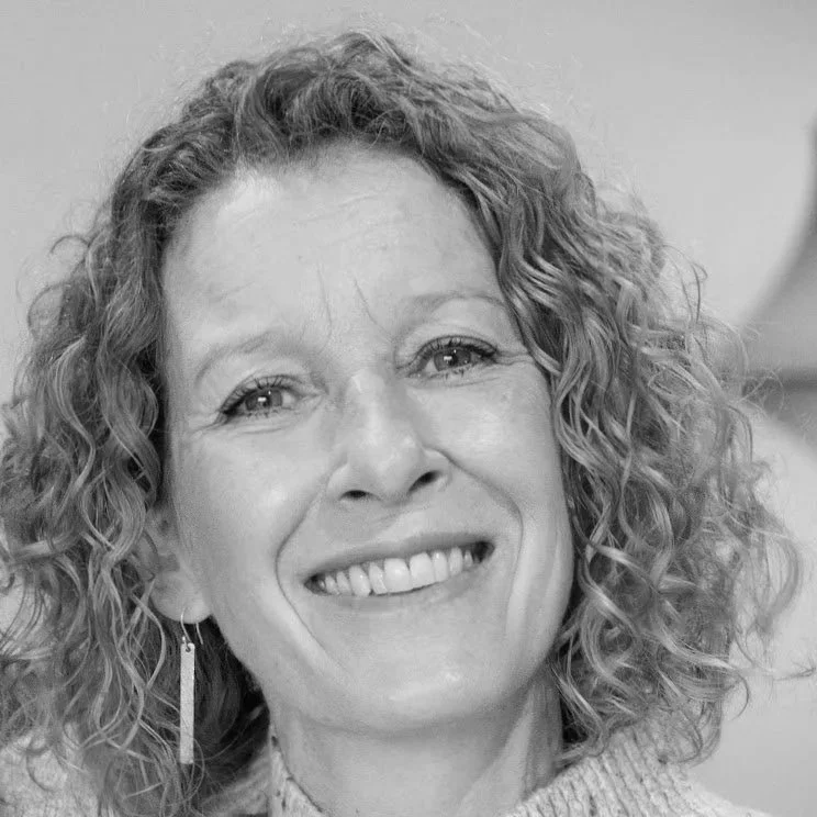 Black and white close-up photo of a smiling woman with curly hair and earrings.