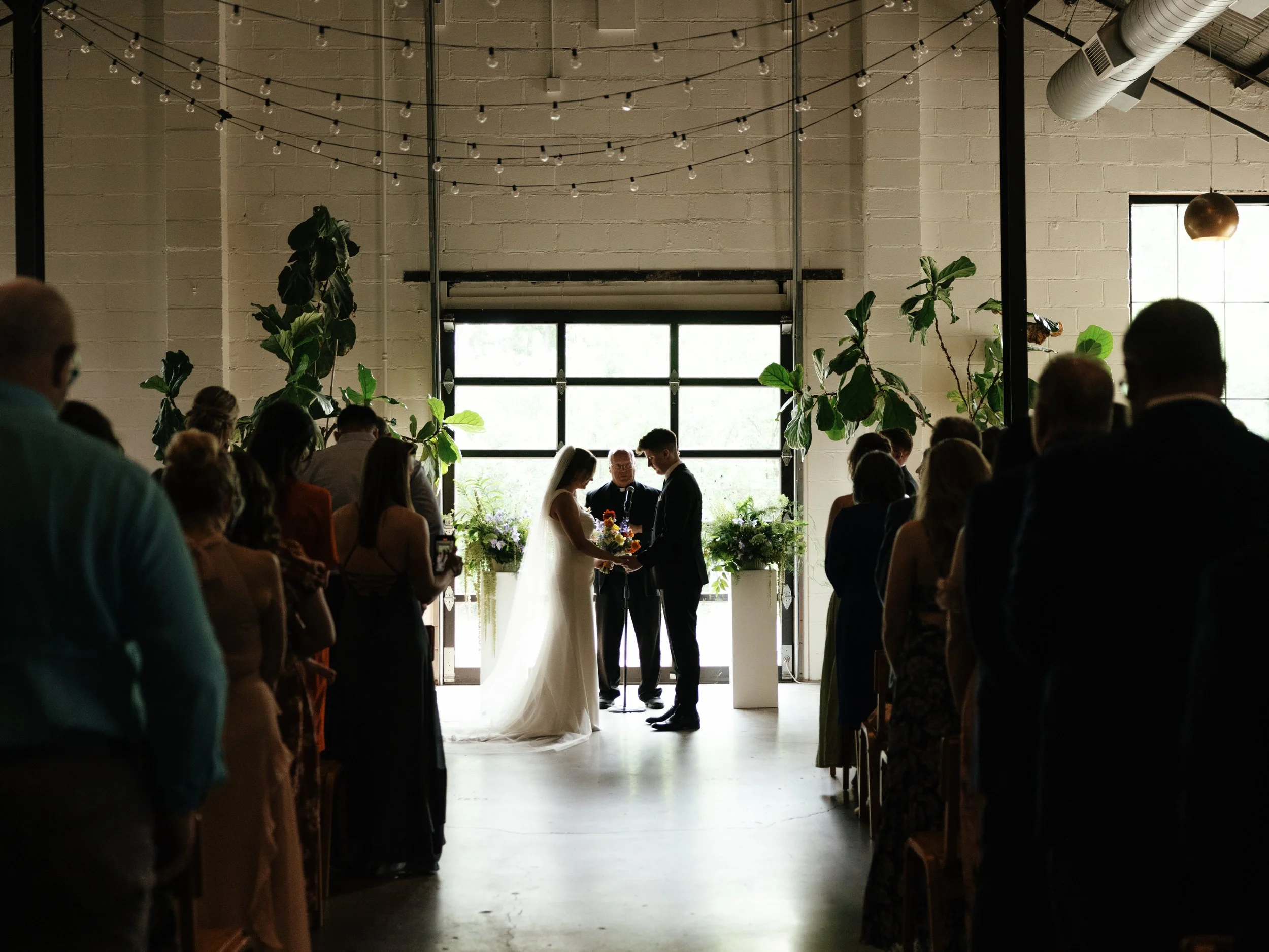 wedding ceremony in front of glass doors with floral pedestals in the background, PAIKKA wedding in St Paul MN