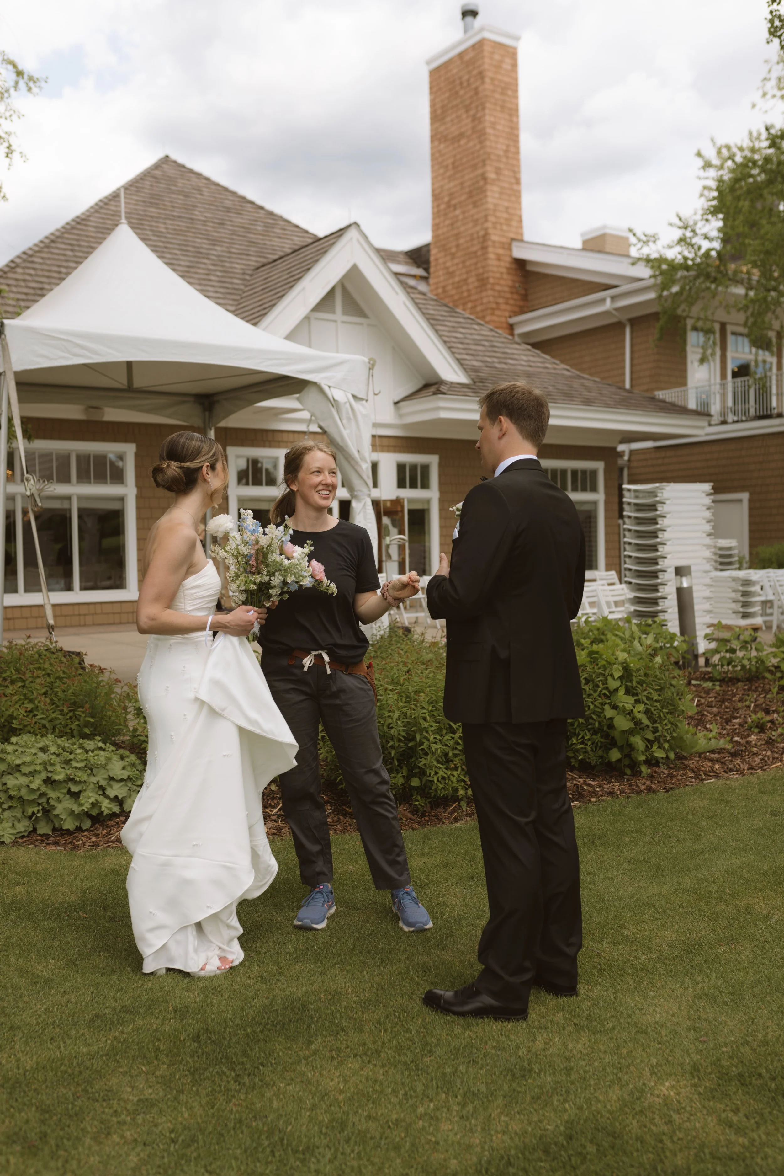 wedding florist chats with bride + groom outdoors