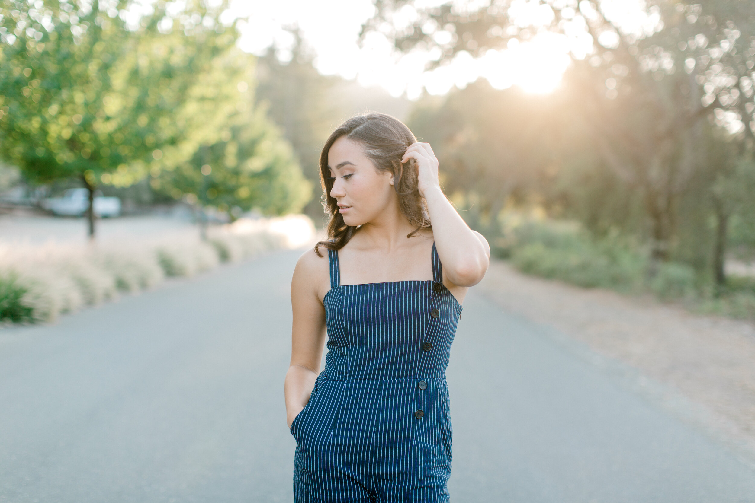 high school senior playing with hair in the road at sunset.jpg