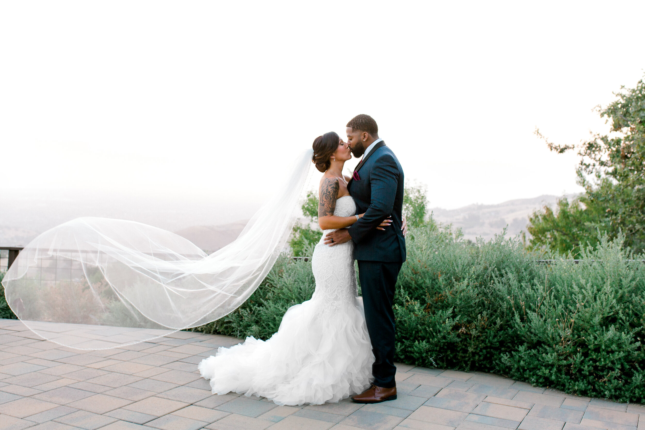 bride and groom kissing at sunset with veil blowing in the wind at grandview restaurant on mount hamilton.jpg